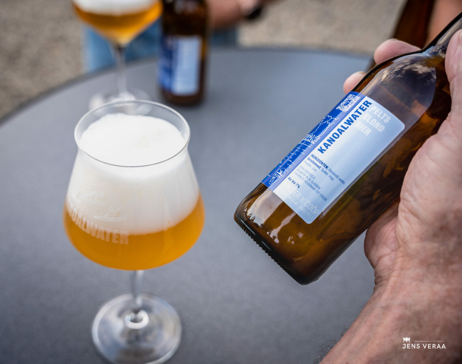 Kanoalwater fles met label naast een glas blond bier.